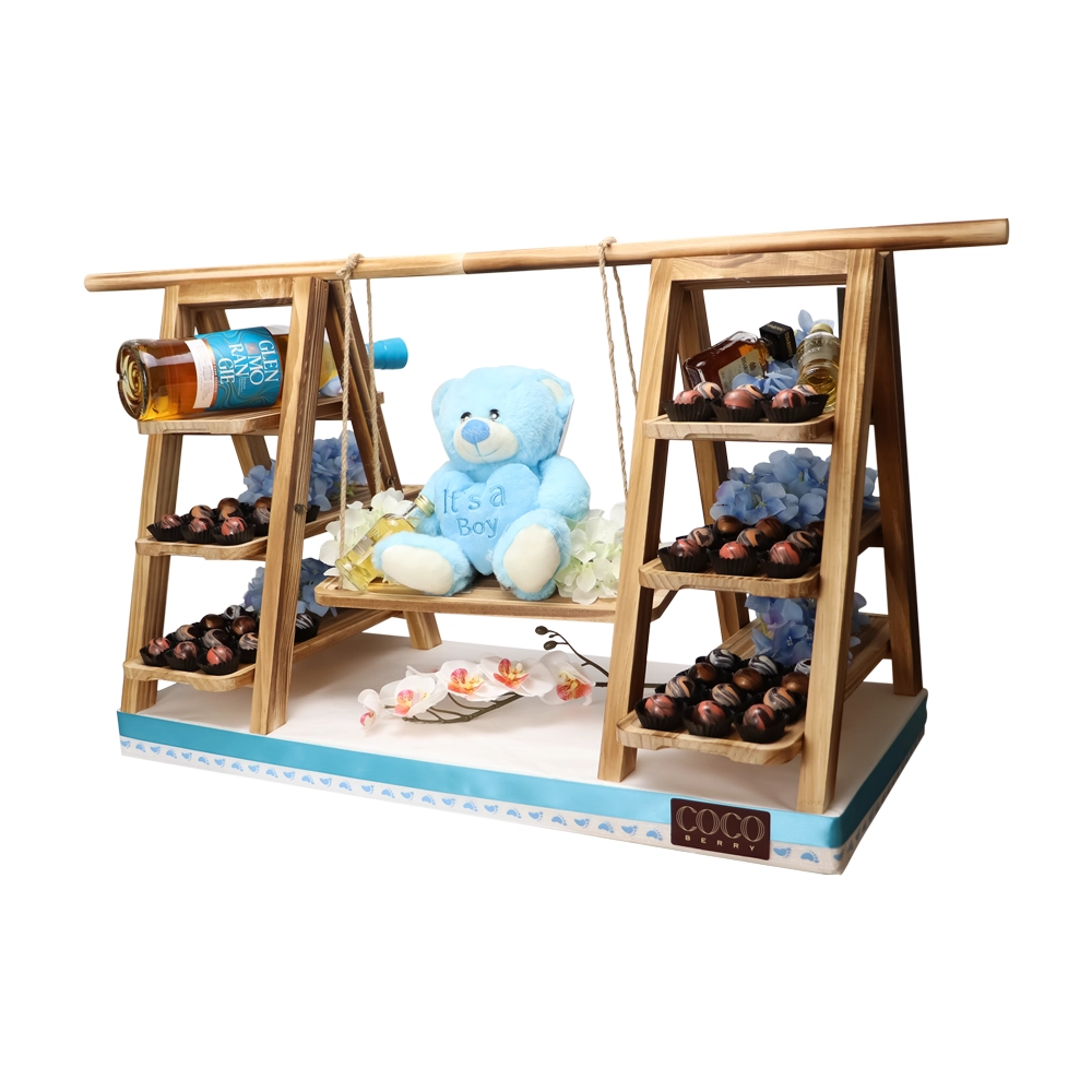 Wooden swing arrangement with chocolates and a blue teddy